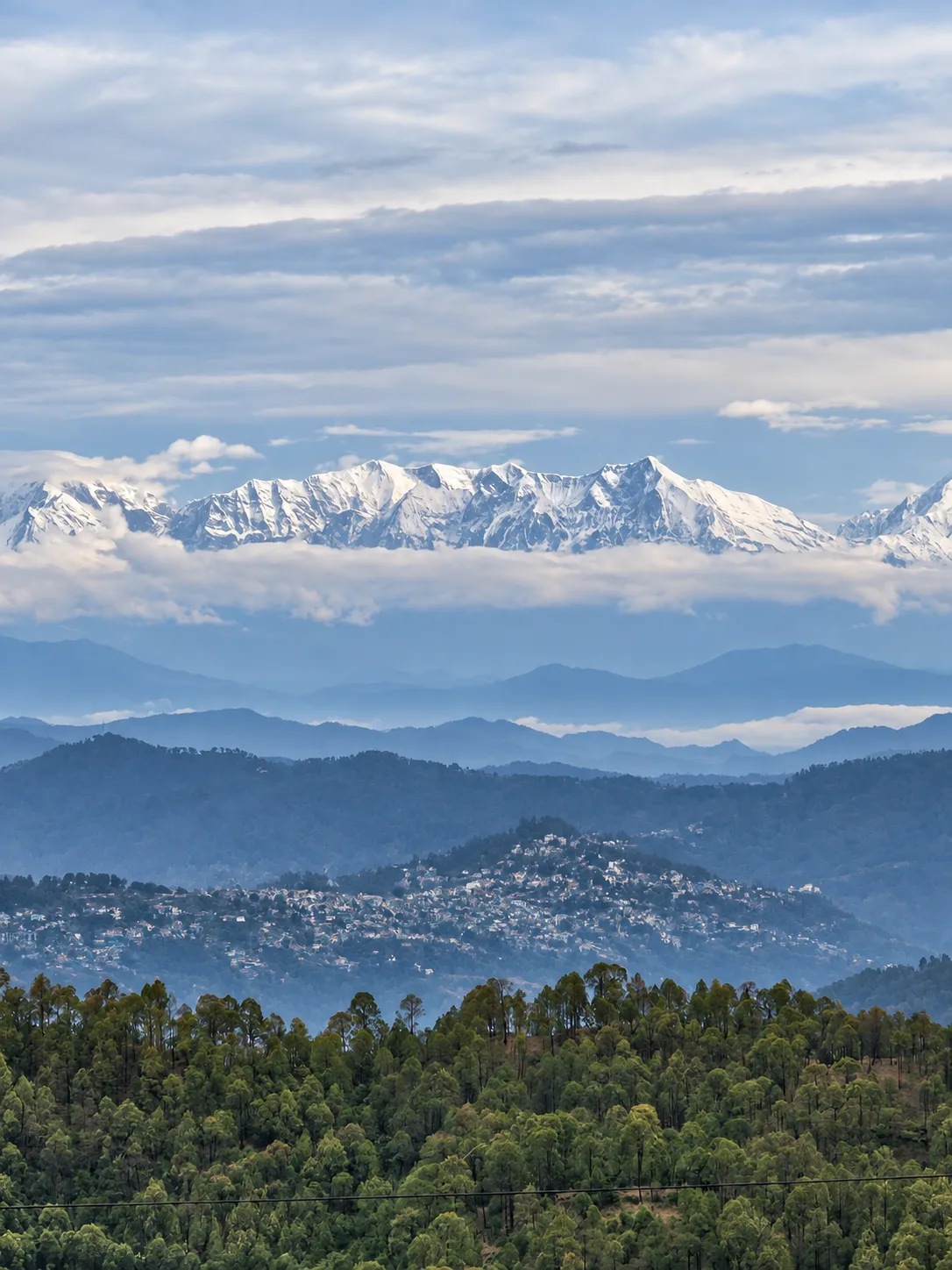 Snow-capped Himalayan peaks above layers of forested hills, seen from the property